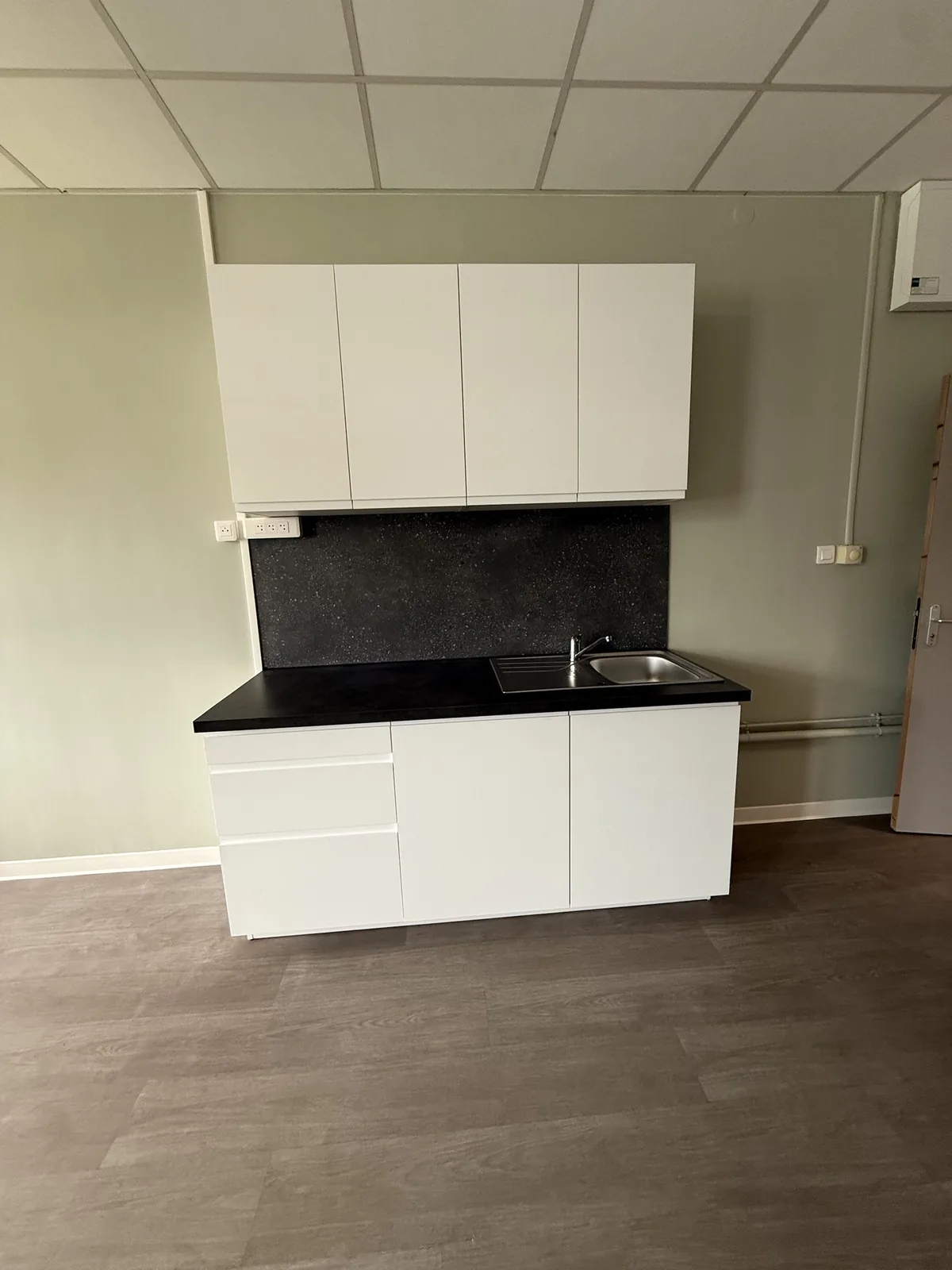 Kitchenette blanche avec plan de travail noir posée sur le même mur