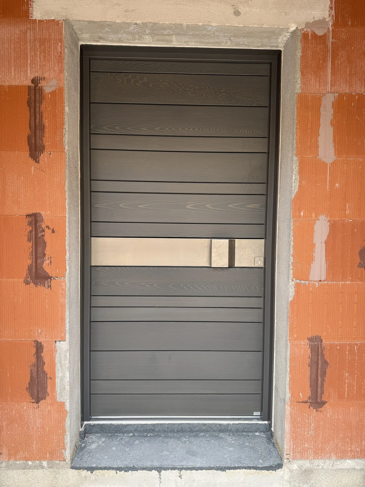 Porte d'entrée en aluminium gris aspect bois, barre de tirage inox