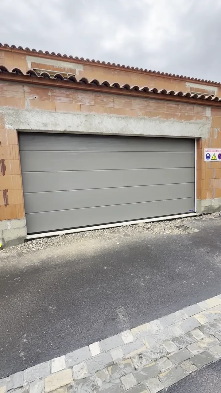 Porte de garage sectionnelle grise sur une maison neuve